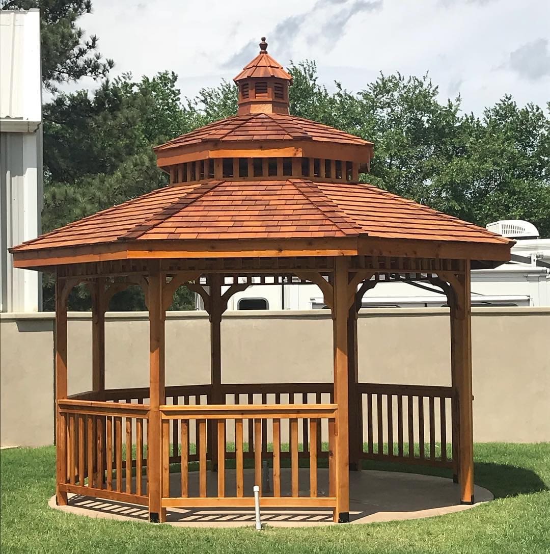 A wooden gazebo in the middle of a yard.