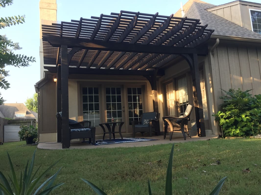 A patio with a pergola and chairs outside