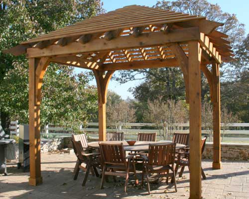 A wooden gazebo with tables and chairs around it.