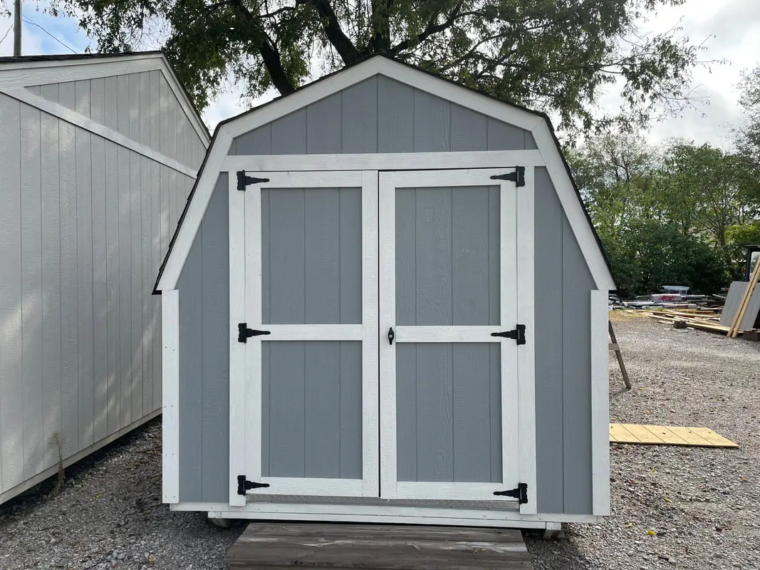 A gray shed with white trim and two doors.