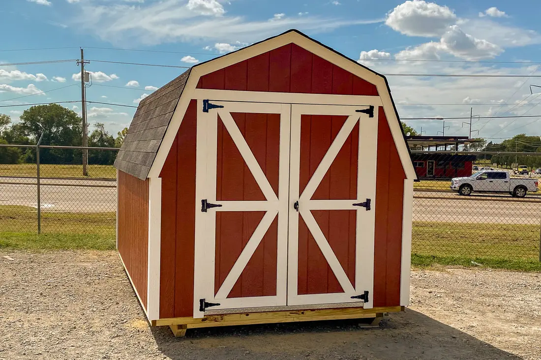 A red shed with two doors and a white trim.