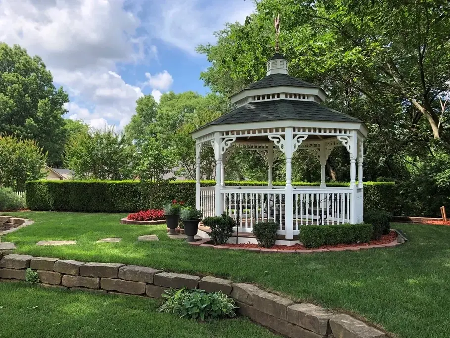 A gazebo in the middle of a park with trees.