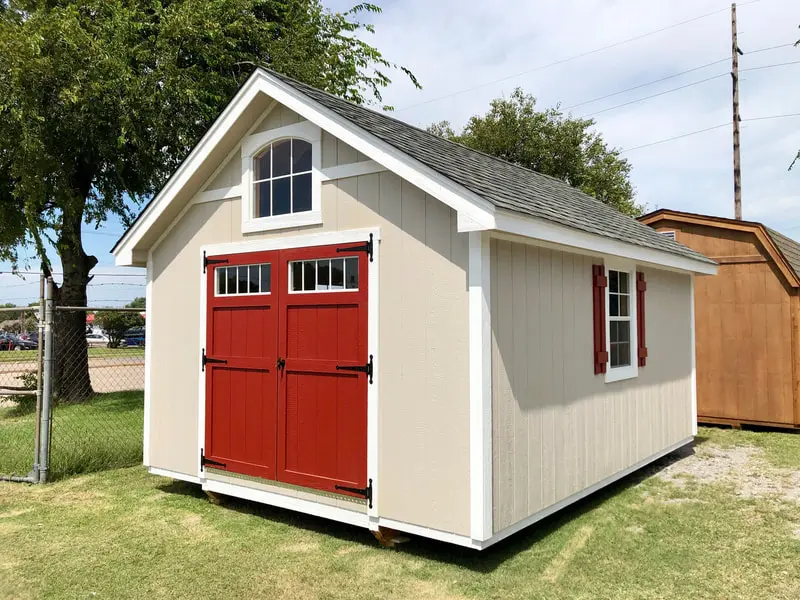 A white shed with red doors and windows.