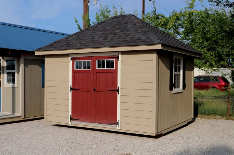 A tan shed with red doors and windows.