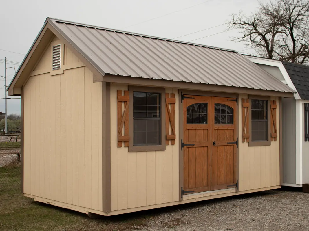 A shed with two windows and shutters on the front.