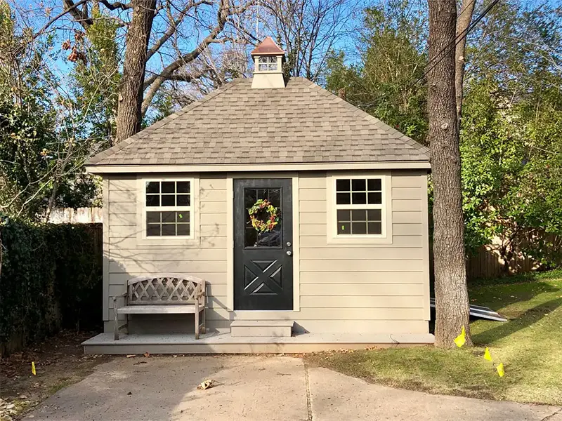A small white shed with a wreath on the door.