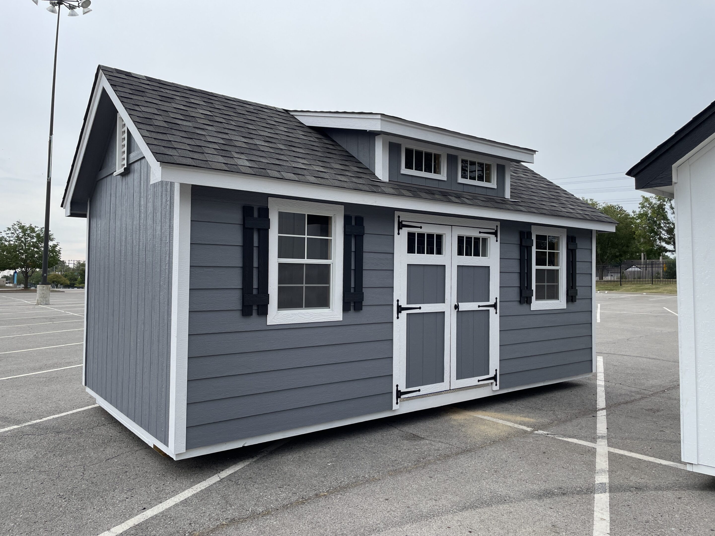 A gray shed with two windows and shutters.