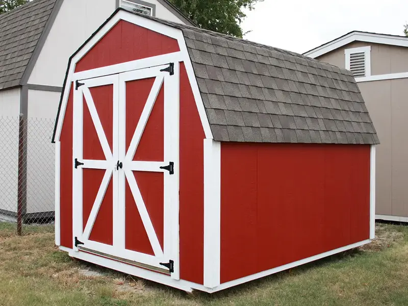 A red and white shed with a black roof