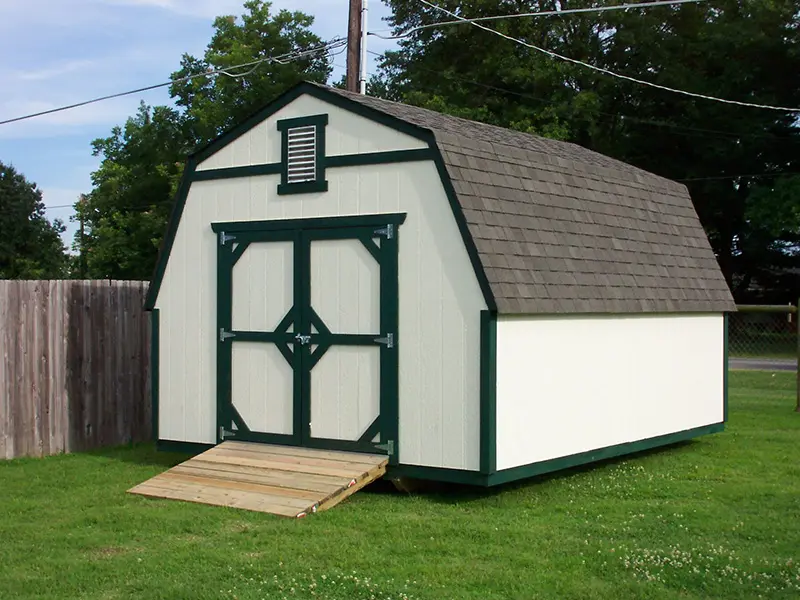 A white shed with green trim and a ramp.