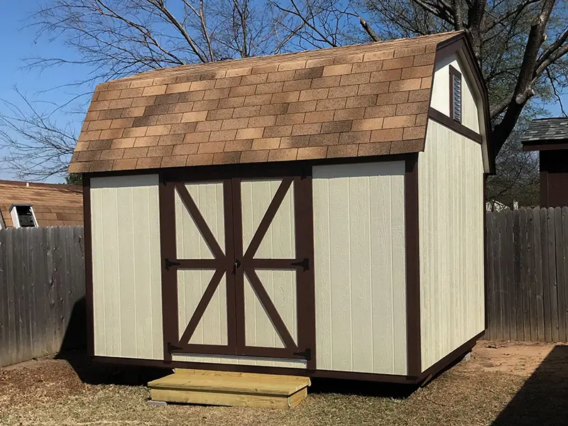 A small shed with brown trim and white siding.