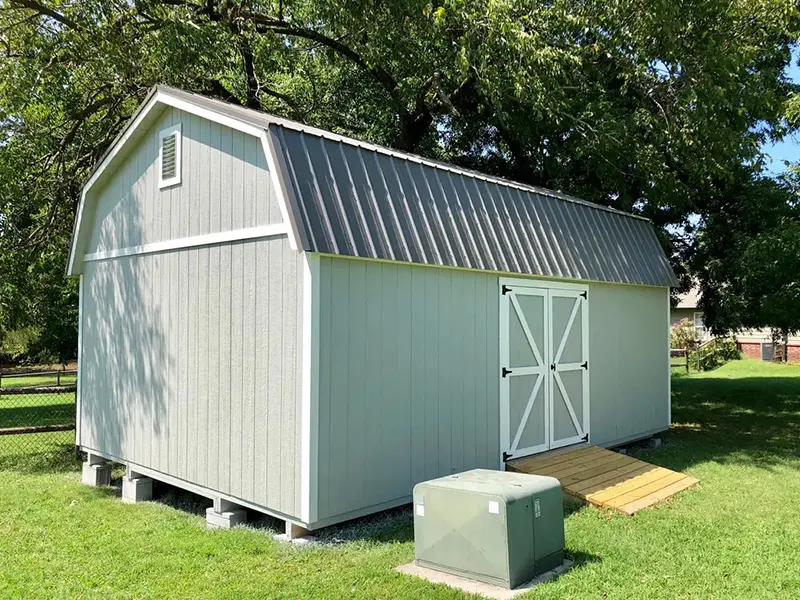 A white shed with metal roof and stairs leading to it.