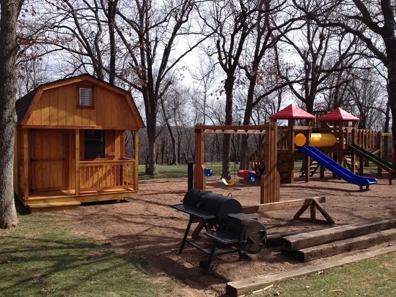 A wooden play set with swings and slides.