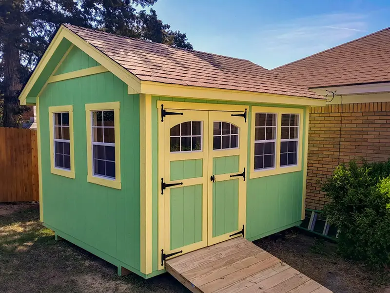 A green shed with yellow trim and a ramp.