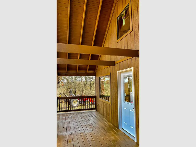 A porch with wood paneling and a white door.